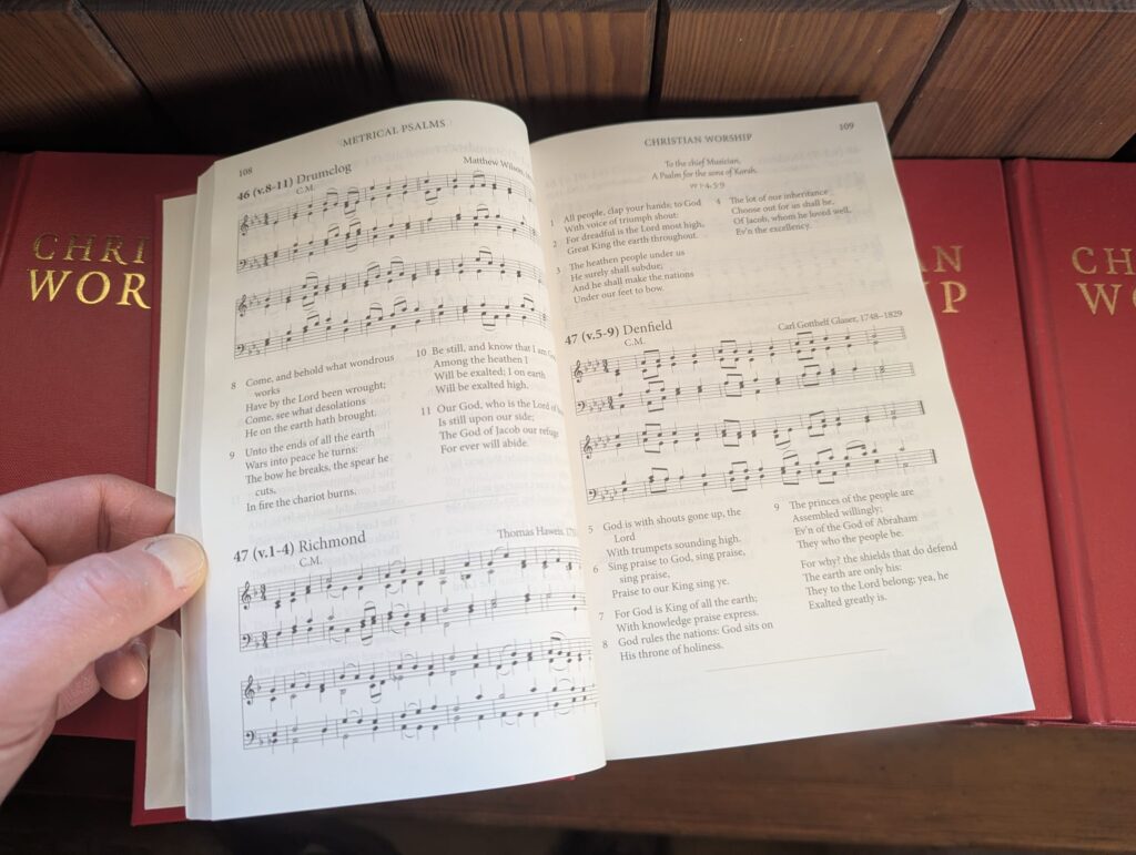 The newly published Combined Words and Music Hymnbook opened on pages showing Psalm 46 verses 8-11 set to tune Drumclog; Psalm 47 verses 1-4 set to Richmond, and 47 verses 5-9 set to Denfield.